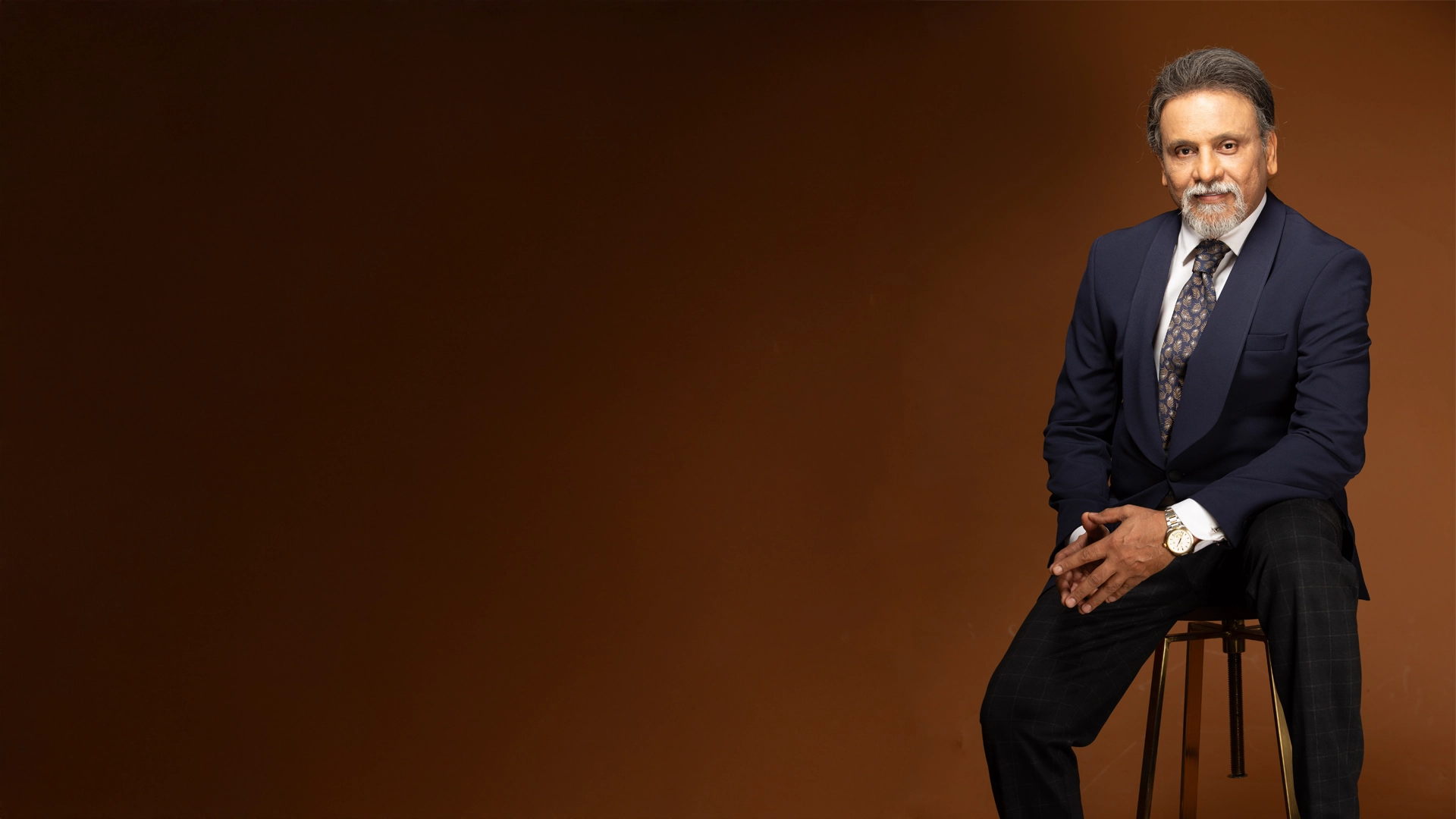 Dr. Sanjay Parashar, plastic surgeon in Dubai, seated in a navy suit